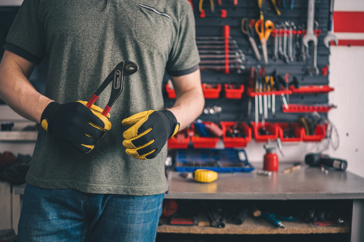 Worker Holding Pliers At Workbench